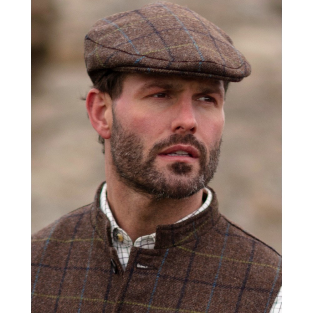Male model wearing a Walker & Hawkes Alfred cap in brown.
