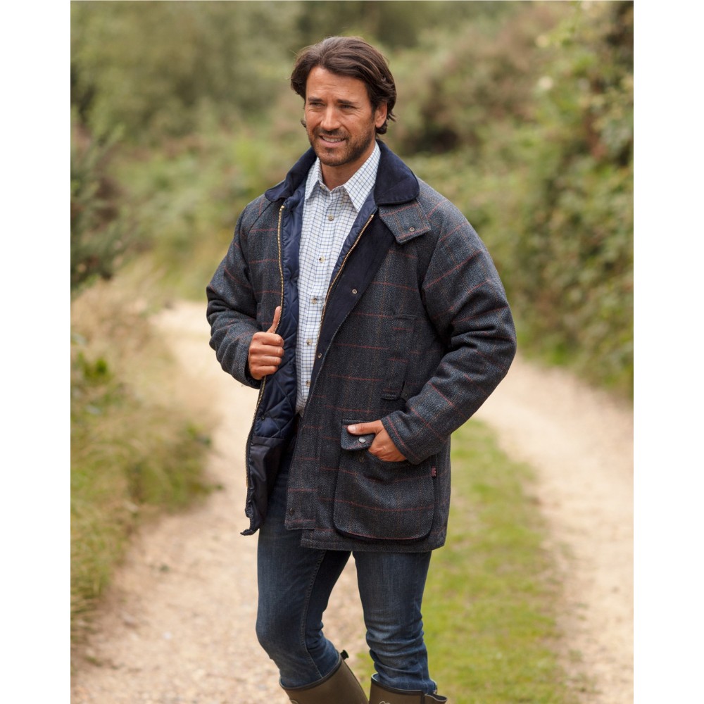 Male model stood on a country path wearing a Walker & Hawkes Barlaston tweed jacket in blue tweed.