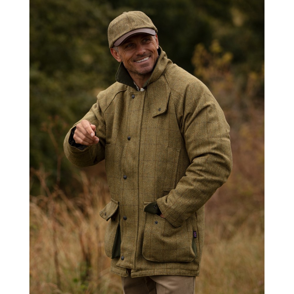 Male model stood on the heath wearing a Walker & Hawkes Barlaston tweed jacket in light sage.