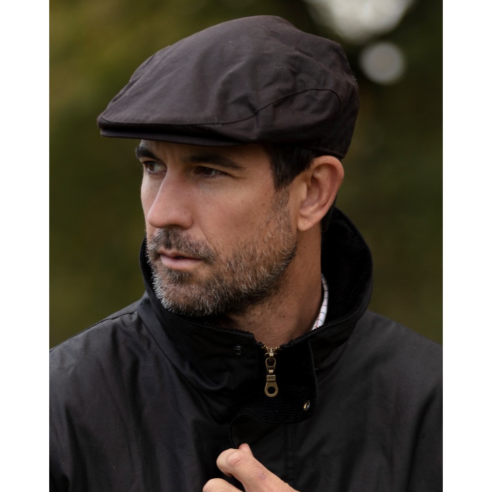 Male model wearing a Walker & Hawkes Belton flat cap in brown.