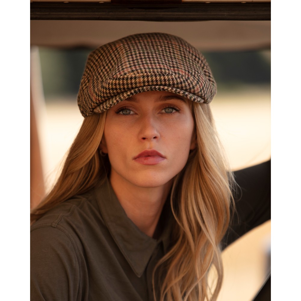 Female model wearing a Walker & Hawkes Braxton flat cap in beige.