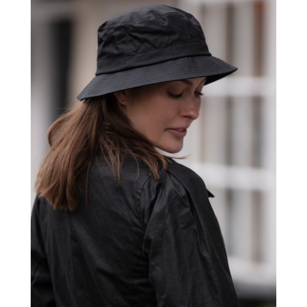 Female model wearing a Walker & Hawkes wax Hanford bucket hat in black.