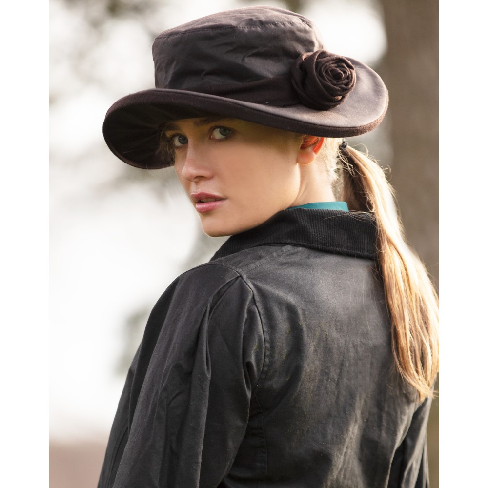Female model wearing a brown Walker & Hawkes Ladies Wax Windsor Rose hat with floral detail.