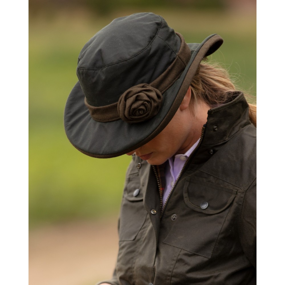 Female model wearing an olive Walker & Hawkes Ladies Wax Windsor Rose hat with floral detail.