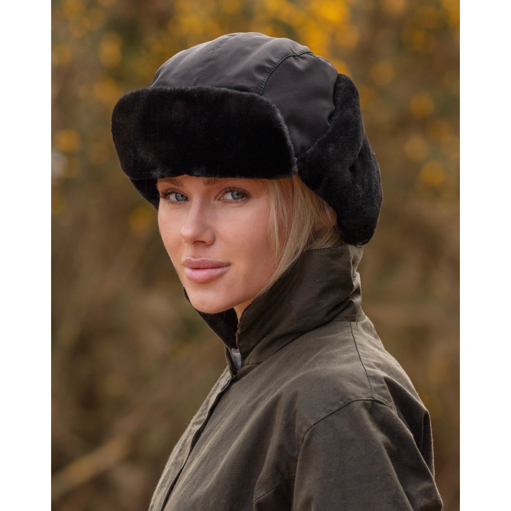Female model wearing a Walker & Hawkes faux fur Harrison trapper hat in black.