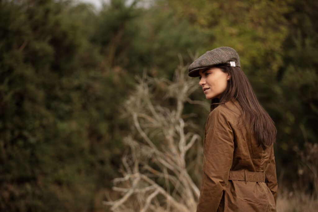 Woman walking on some moorland, wearing a hat and jacket from Walker & Hawkes.